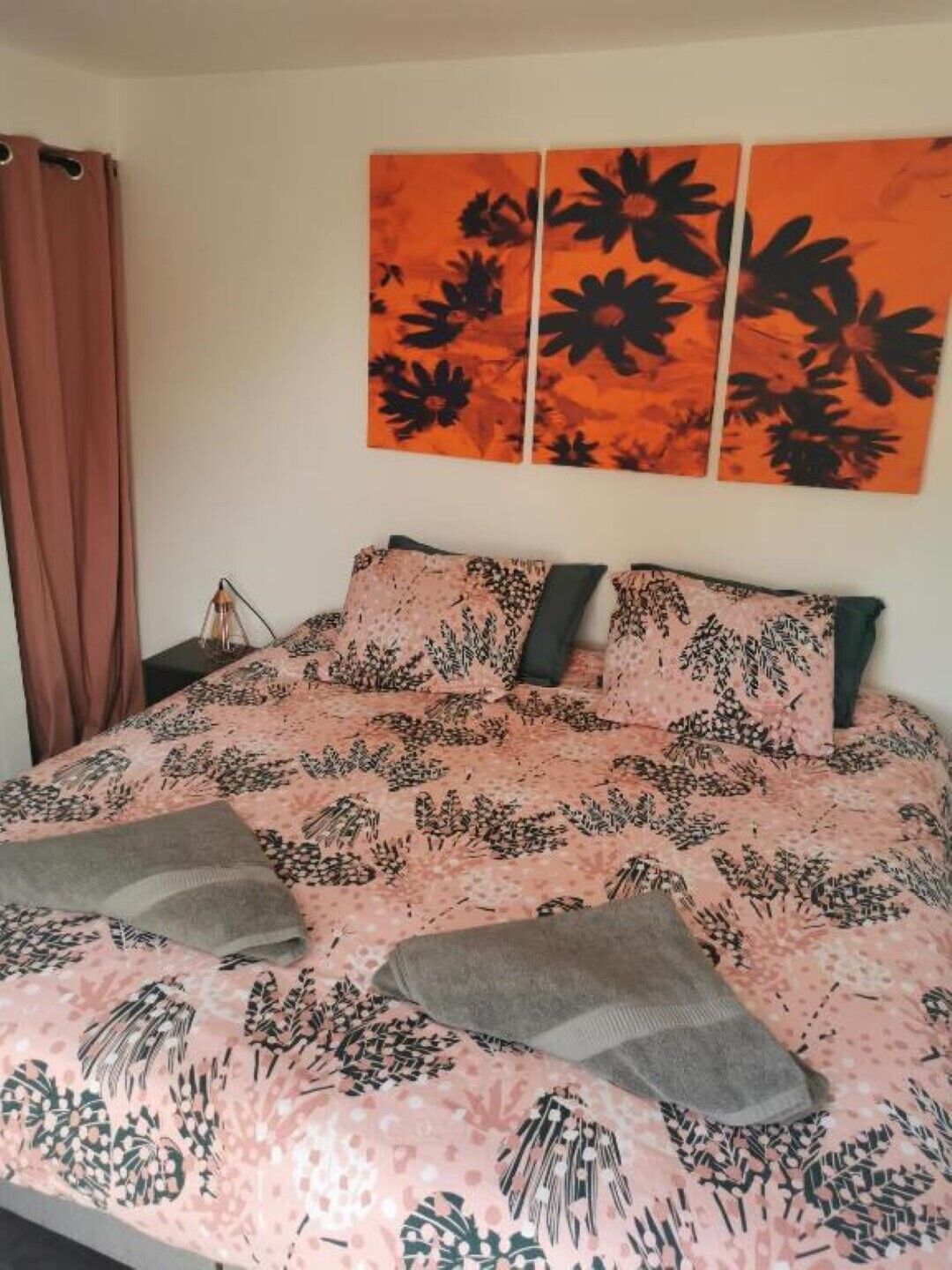 A bedroom with a bed, a nightstand, and a wall-mounted painting.