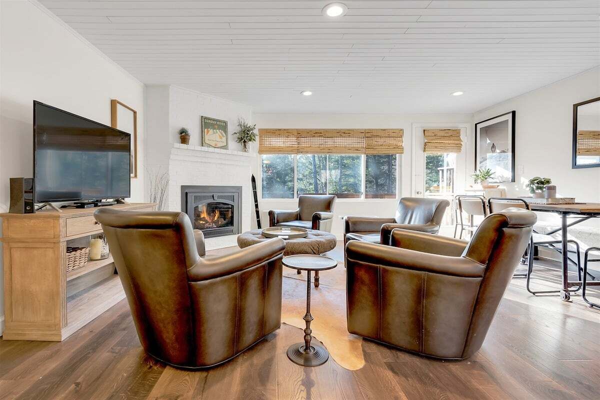 A living room with a fireplace, leather armchairs, a TV, and a dining area.
