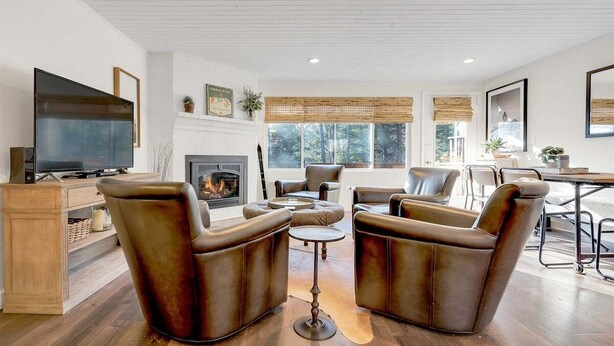 A living room with a fireplace, leather armchairs, a TV, and a dining area.