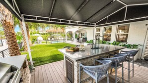Eine Außenpatio mit Barbereich, Sitzgelegenheiten und Blick auf Pool und Garten.