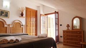 A bedroom with a bed, wooden headboard, a dresser, and a mirror. - Panoramic Santa Domenica (Santa Domenica)