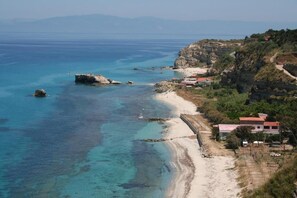 A coastal area with a beach, rocky outcrops, and buildings. - Panoramic Santa Domenica (Santa Domenica)