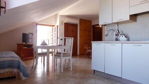 A bedroom with a bed, a TV, and a window. There is a kitchenette with a sink and cabinets. - Panoramic Santa Domenica (Santa Domenica)