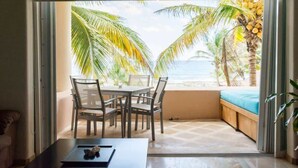 A room with a sliding glass door leading to a balcony with a view of palm trees and the sea.