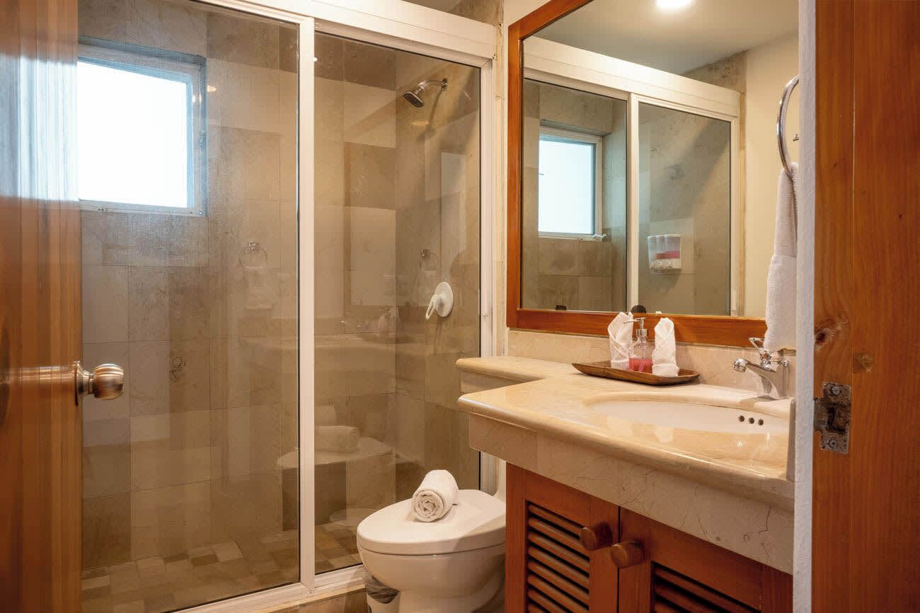 Un bagno con doccia vetrata, un water, un lavandino con specchio e un porta asciugamani.