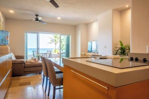 A modern kitchen with a large island, a dining area with a view, and a ceiling fan.