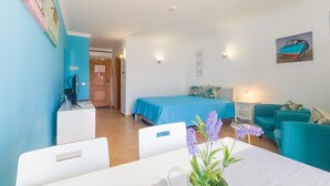 A room with a bed, a desk, a chair, a table, a couch, and a wall-mounted lamp. - Casa Andorinhas - Quinta Velha Village - Free WiFi and Meo (Cabanas de Tavira)