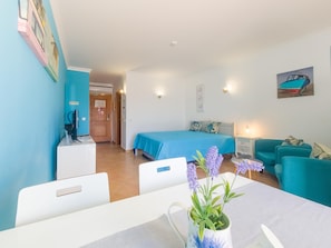 Une pièce comprenant un lit, un bureau, une chaise, une table, un canapé et une lampe fixée au mur.