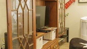 Ein Zimmer mit einem Holzschrank mit Glastüren, einem Fernseher und einer roten Pfeil-Dekoration an der Wand.
