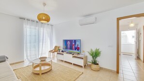 A modern living room with a TV, sofa, coffee table, and a potted plant.