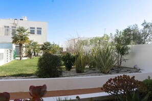 Un jardín ajardinado con diversas plantas y un edificio moderno al fondo.
