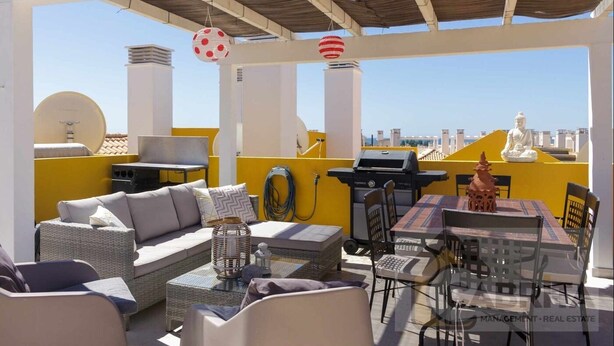 Eine Dachterrasse mit Sitzgelegenheiten im Freien, einem Grill und einer Buddha-Statue.