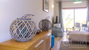 Ein Hotelzimmer mit einem Holzkasten, zwei dekorativen Korbwannen, einem Fernseher, einer Couch und einem Essbereich mit Tisch und Stühlen.