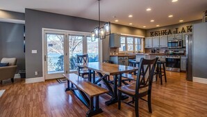 Une cuisine moderne dotée d’un grand îlot central, d’appareils électroménagers intégrés et d’un coin repas avec des tables et des bancs en bois.