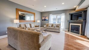 Un salon avec deux canapés, une table basse, une cheminée et un grand miroir au mur.