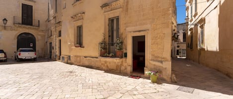 A cobblestone street in a historic town with buildings featuring arched doorways and windows with shutters.