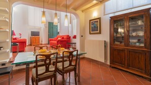 Un coin repas avec une table et des chaises en verre, un canapé rouge et un meuble en bois doté de portes en verre.