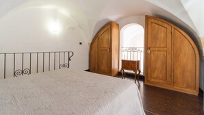 Une chambre à coucher avec un lit, une armoire en bois et un plafond en arc de cercle.