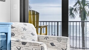 Un balcone con vista sul mare, un mobile azzurro e una sedia a motivi decorativi.