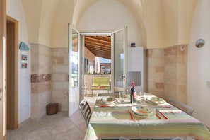 A dining area with a table set for four, a bottle of wine, and a view of the outside.