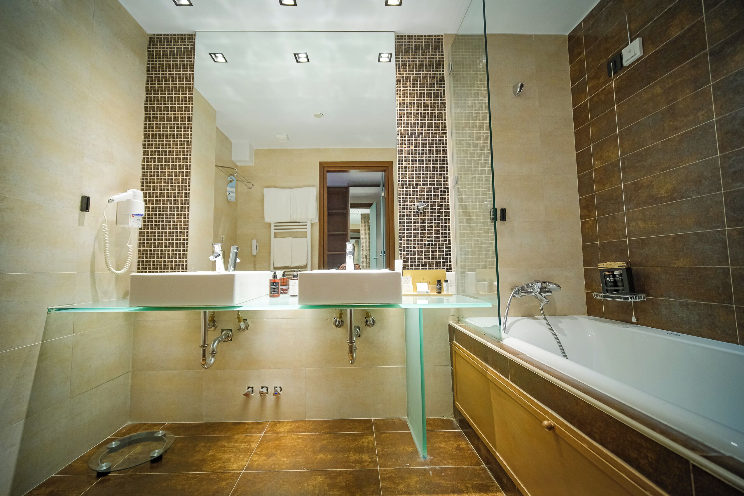 Een moderne badkamer met twee wasbakken, een douchecabine met glazen wanden en een bad.