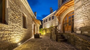 Un callejón empedrado con escalones y puerta de madera, que conduce a un edificio de fachada de piedra.