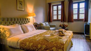 Un dormitorio elegante con una cama grande, una mesita de noche con lámpara, una silla y vistas al exterior a través de una ventana.