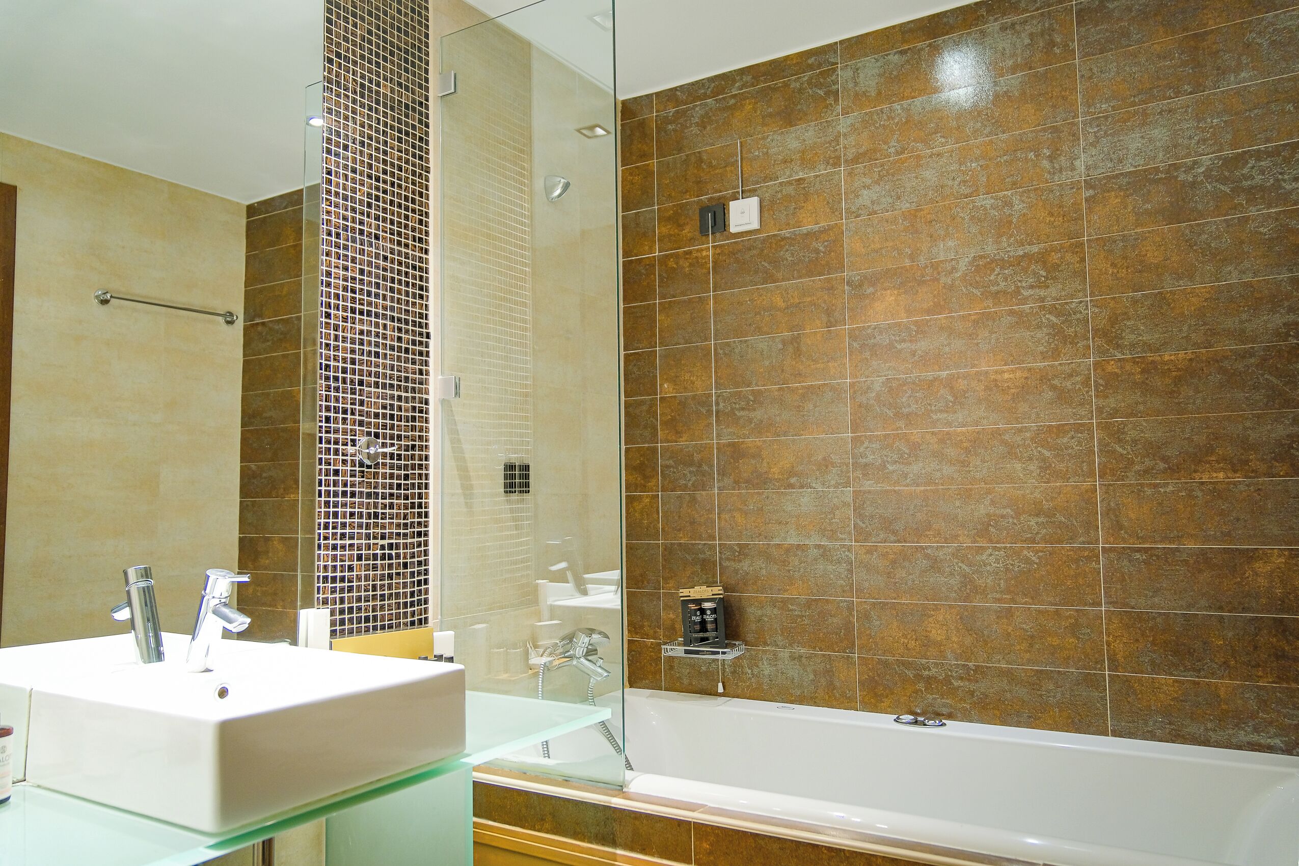 A bathroom with a white sink, glass shower enclosure, and a bathtub.