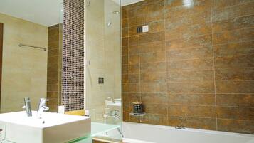 A bathroom with a white sink, glass shower enclosure, and a bathtub.