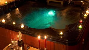 Un jacuzzi con velas y una botella de champán sobre una bandeja.