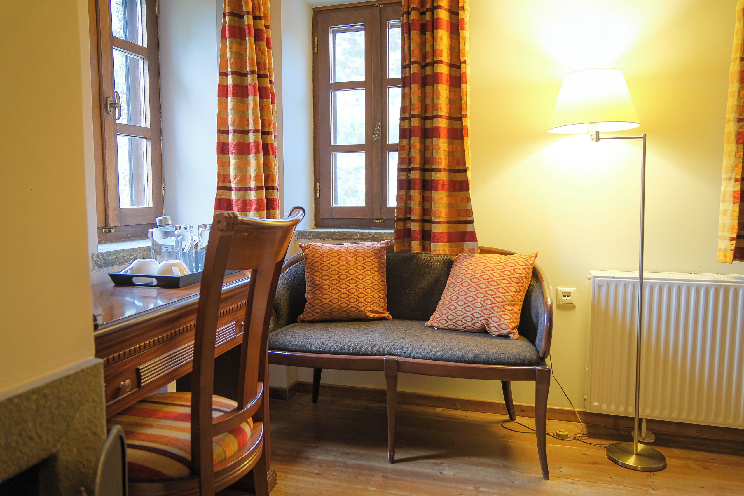 A cozy room with a wooden dining table, a cushioned bench, and a floor lamp.