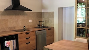 Uma cozinha moderna com forno embutido, máquina de lavar louça e uma mesa de jantar de madeira com cadeiras.