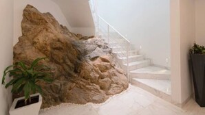 A modern interior with a large rock feature, a staircase, and a potted plant. - Pedregal 9 BR Villa Tanzanita (Cabo San Lucas)