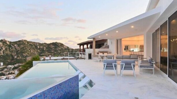 A modern outdoor living area with a pool, seating, and a view of the surrounding landscape. - Pedregal 9 BR Villa Tanzanita (Cabo San Lucas)