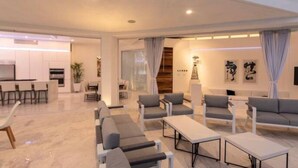 A modern living room with a sofa set, a coffee table, and a dining area with chairs and a table. - Pedregal 9 BR Villa Tanzanita (Cabo San Lucas)