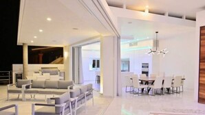 A modern interior with a seating area, dining space, and a large window. - Pedregal 9 BR Villa Tanzanita (Cabo San Lucas)