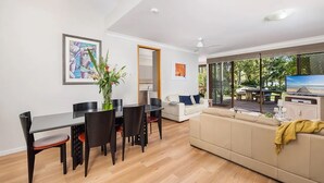 Een moderne woonkamer met een eethoek, een bank en een televisie.