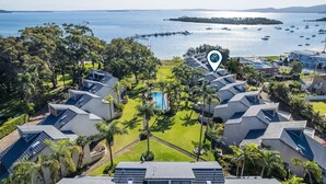 Een resort met meerdere bungalowgebouwen, een centraal zwembad en een jachthaven met boten.