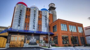 Ein Gebäude mit großen zylindrischen Strukturen, auf denen „SEACRETS“ und „DISTILLING COMPANY“ stehen, sowie ein kleineres Gebäude mit dem Schild „Seacrest Distilling Company“.