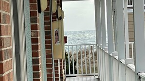 Eine überdachte Holzterrasse mit einer Backsteinmauer an einer Seite und einer Brüstung an der anderen, die zu einem Blick auf den Ozean führt.