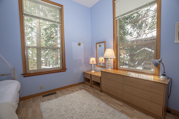 A bedroom with a bed, a dresser, two nightstands, and two lamps.