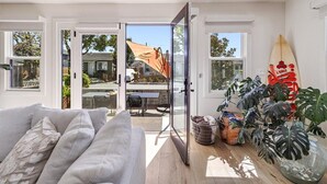 Un interior moderno con un sofá, una tabla de surf y un ventanal de vidrio que da a un espacio exterior.