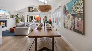 Un comedor moderno con una larga mesa de madera, una lámpara colgante y un cuadro abstracto grande en la pared.