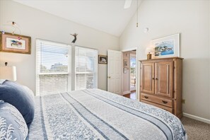 Une chambre à coucher avec un lit, une armoire en bois et une porte donnant sur une autre pièce.