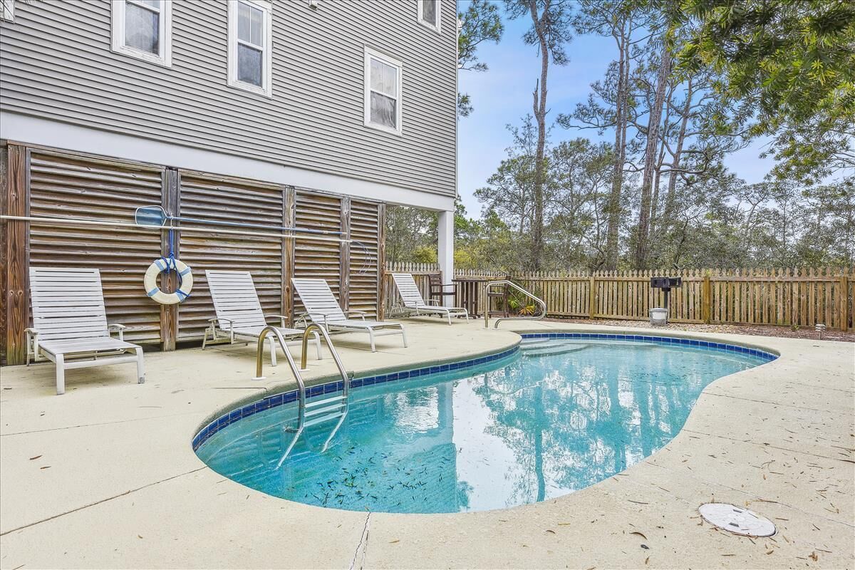 Une piscine avec des chaises longues et une clôture en bois.