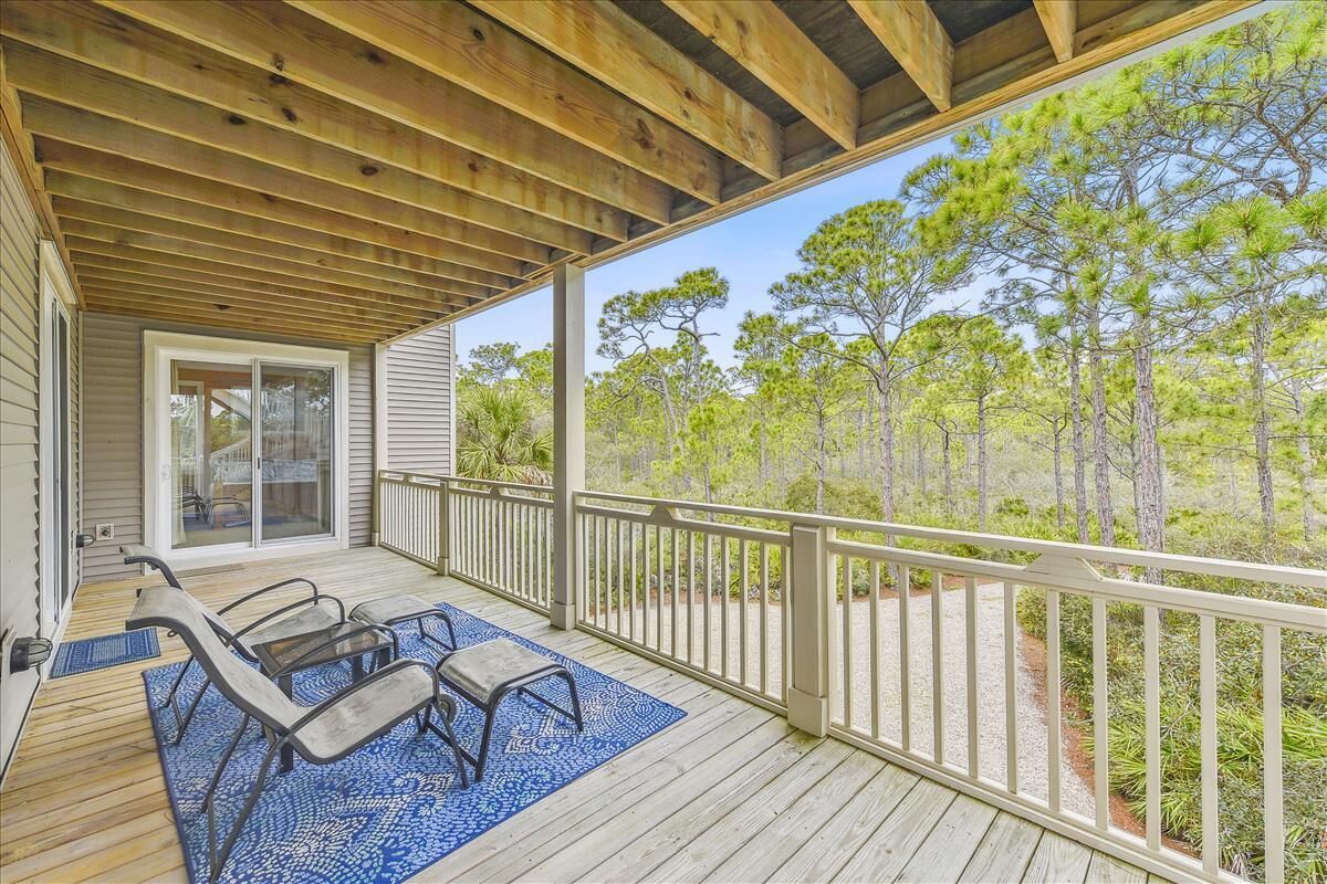 A covered deck with outdoor furniture and a view of a forest.