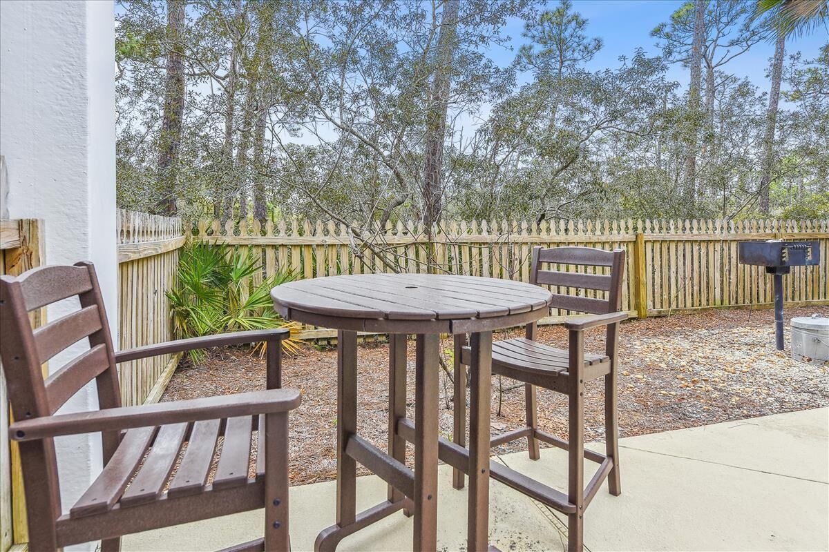 A patio with a round table and two wooden chairs, a wooden fence, and a mailbox in the background.
