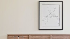 A neatly made bed with white linens, a wooden headboard, and a framed abstract artwork on the wall. - Opal Lofts - Quartier Latin (Montreal)