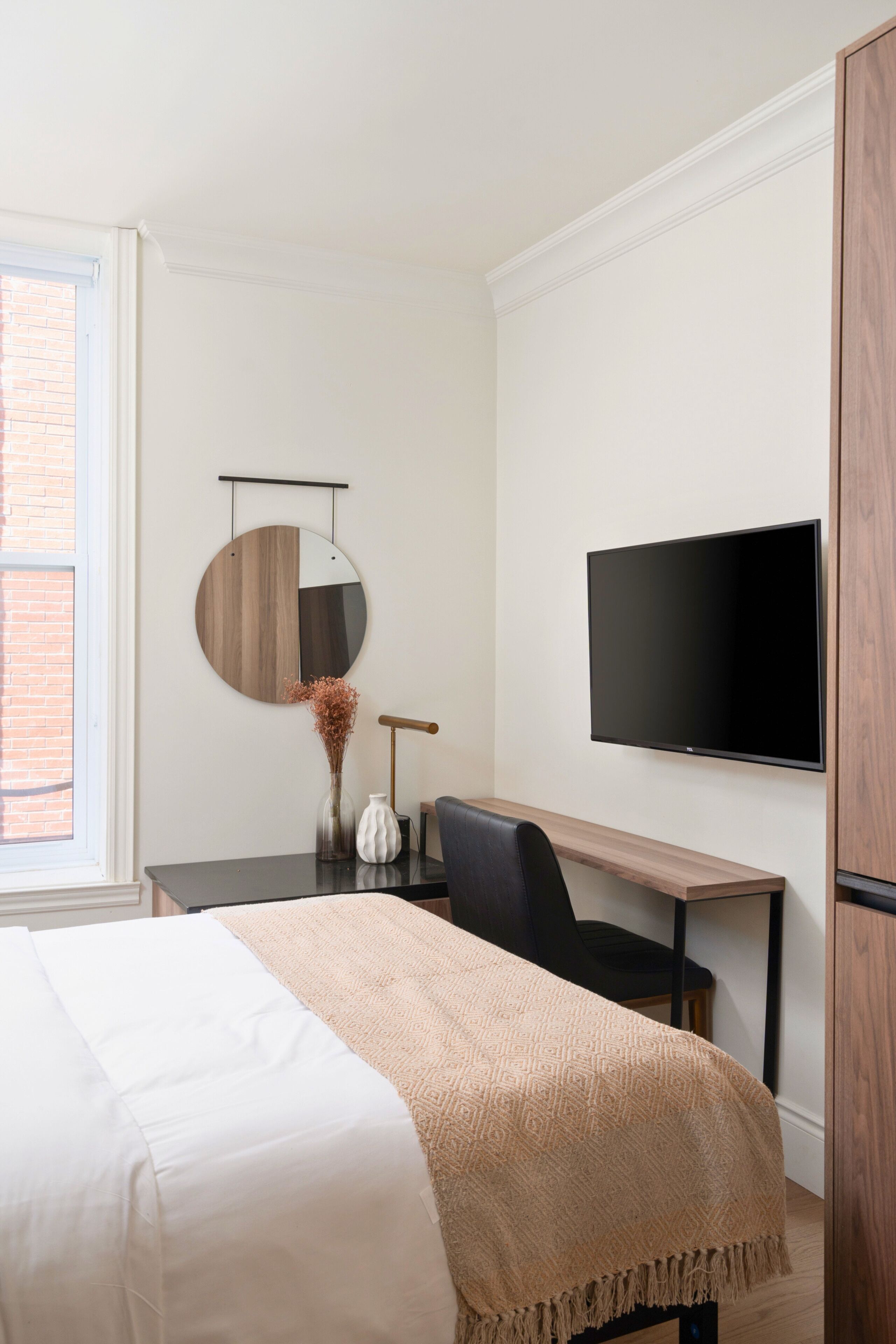 Habitación de hotel con cama, escritorio, silla, televisor y ventana.