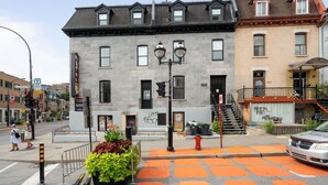 A multi-story building with a grey facade, multiple windows, and a red fire hydrant on the sidewalk. - Opal Lofts - Quartier Latin (Montreal)